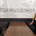 Kristin Marczak standing at a table with a quote displayed on the back of the wall behind her