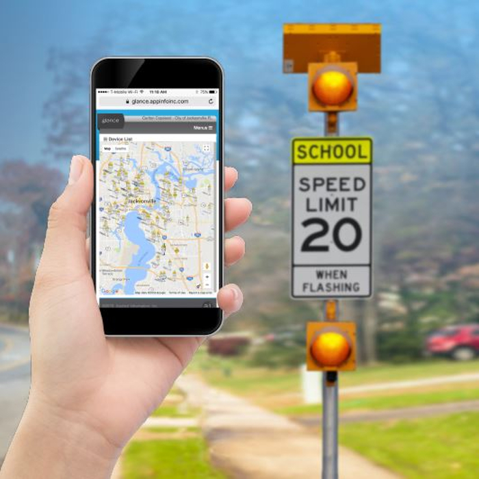 Phone with map held up next to school speed limit sign