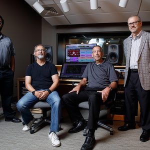 Three men sit in on-campus recording studio