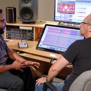 Two men sit at table with recording equipment