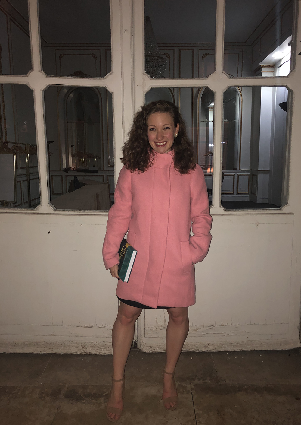 Student in pink coat standing in front of doors