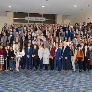 Room full of people in conference center hall pose for picture