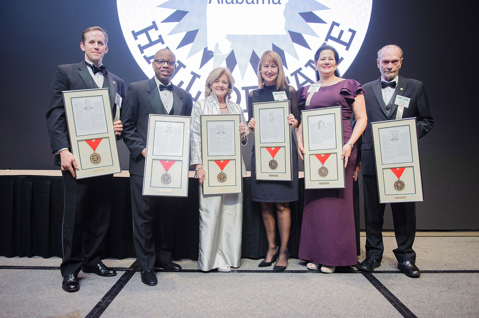 6 people in formal wear holding awards
