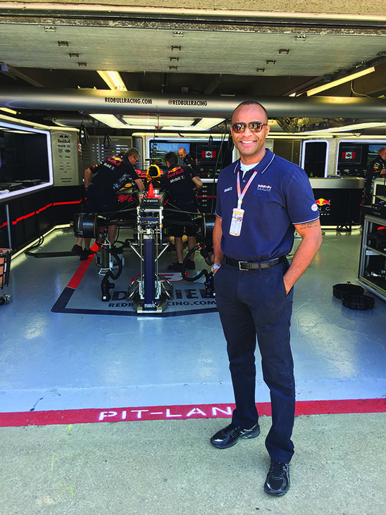 artis brown stands in front of people working on a race car