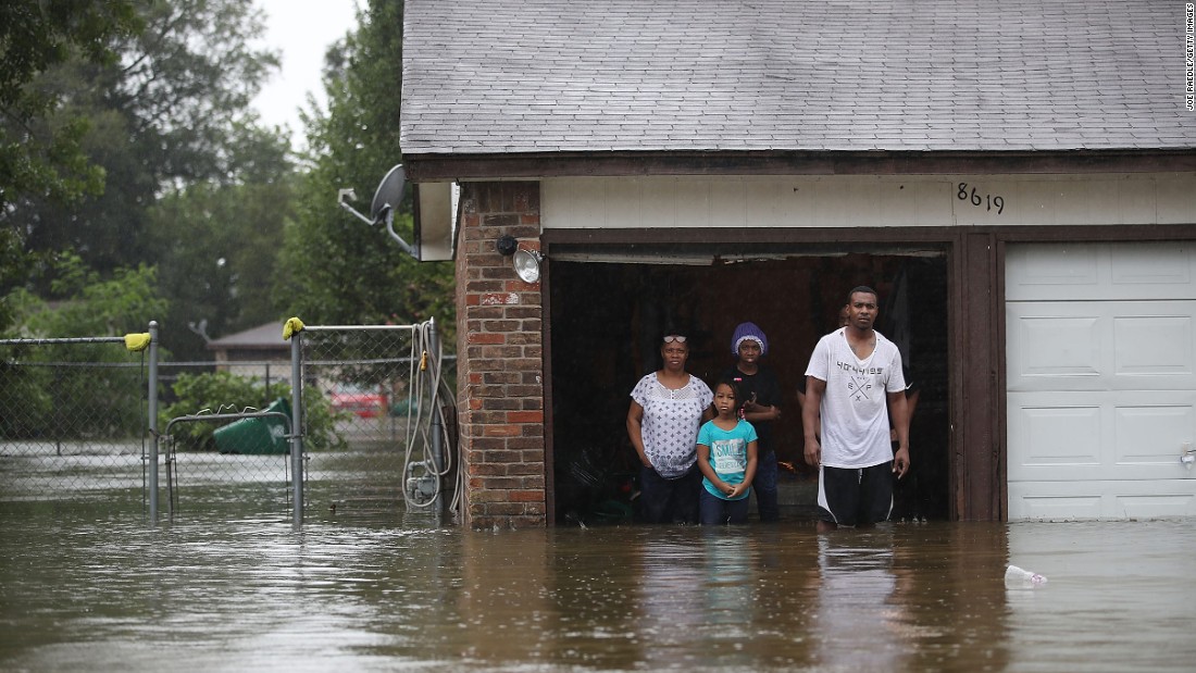 A family stands in their garage amid flood waters up to their knees