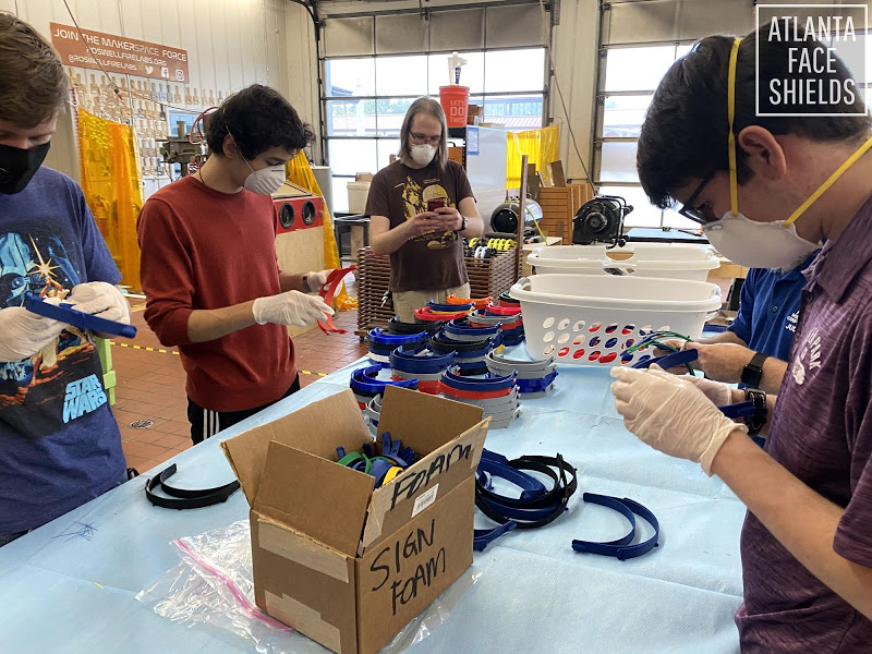 Several people in a lab assembling face shields