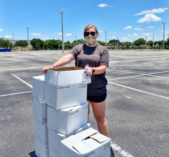 Woman stands in empty parking lot with boxes.