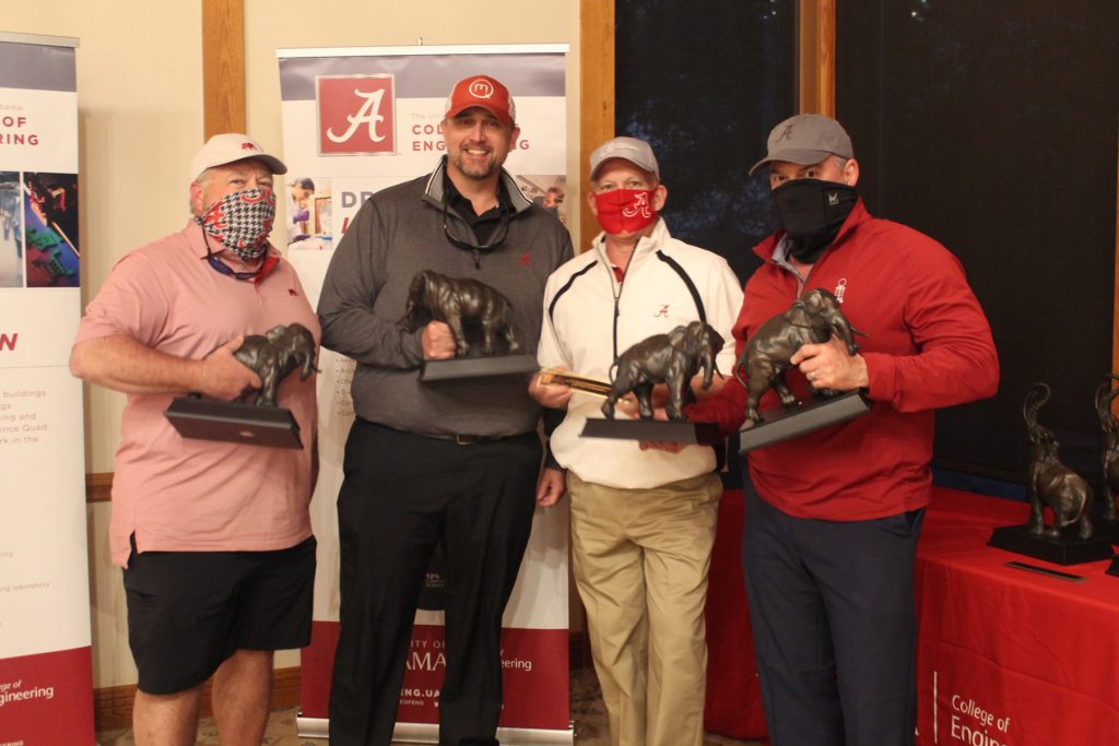 Group photo of 4 in golfing attire holding elephant trophies