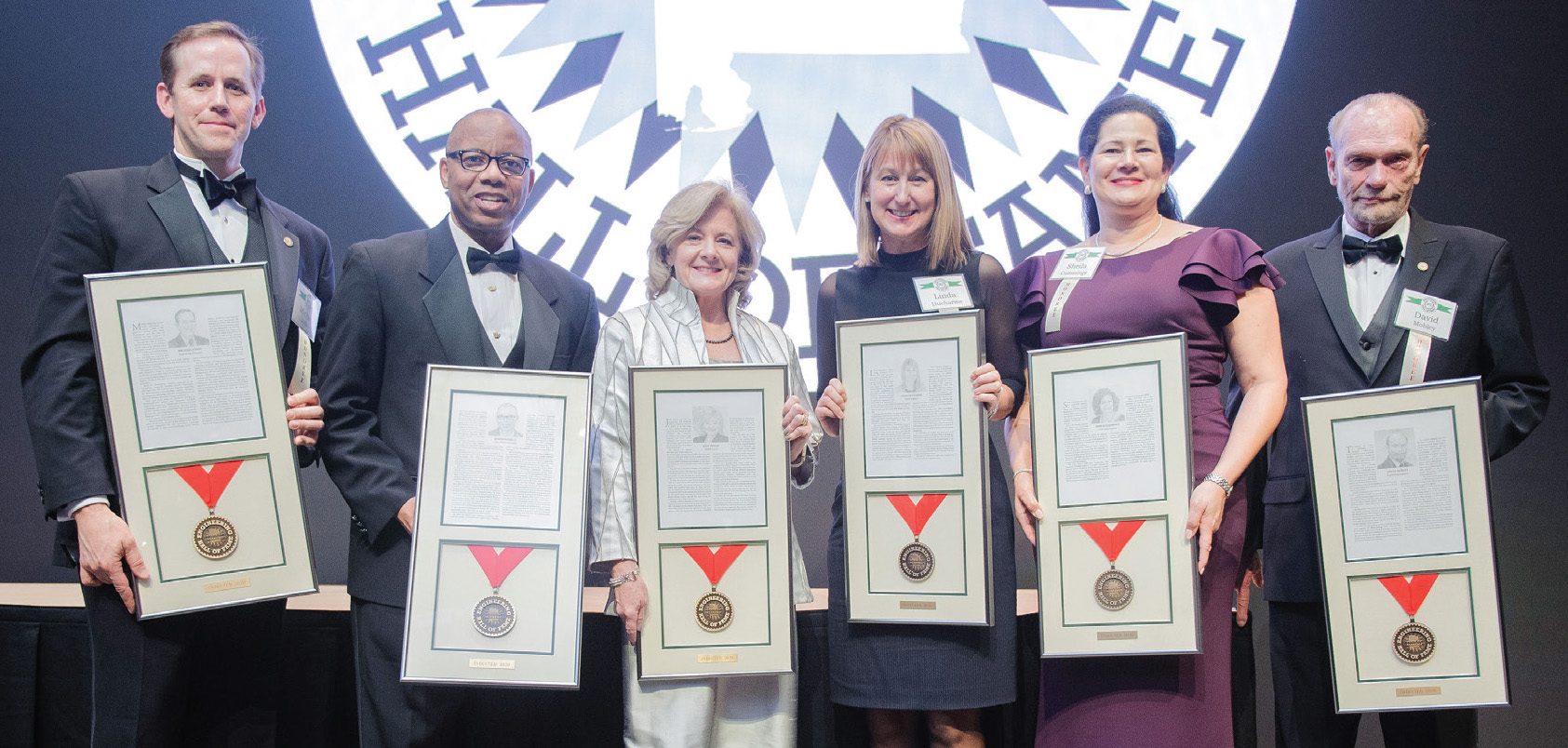 six people holding awards on a stage