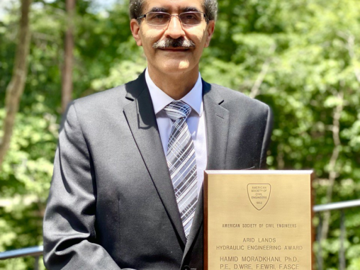 Dr. Hamid Moradkhani holding his award outside on a sunny day