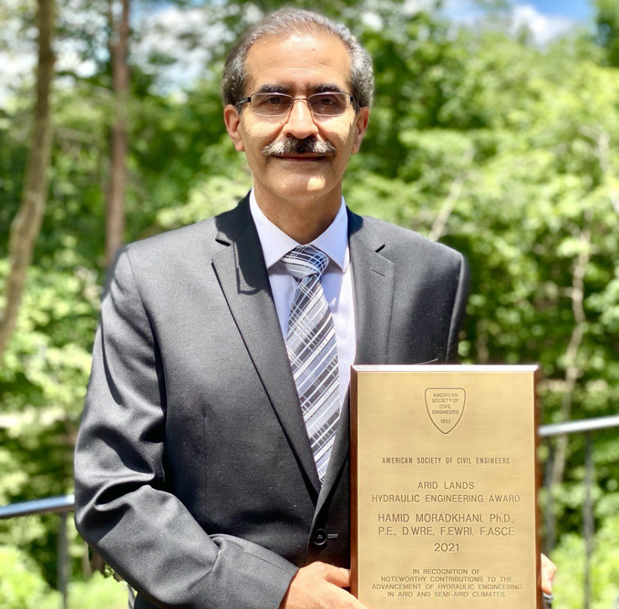 Dr. Hamid Moradkhani holding his award outside on a sunny day