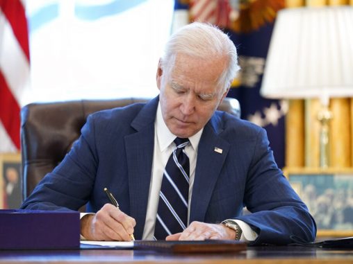 President Biden signing a paper on his desk