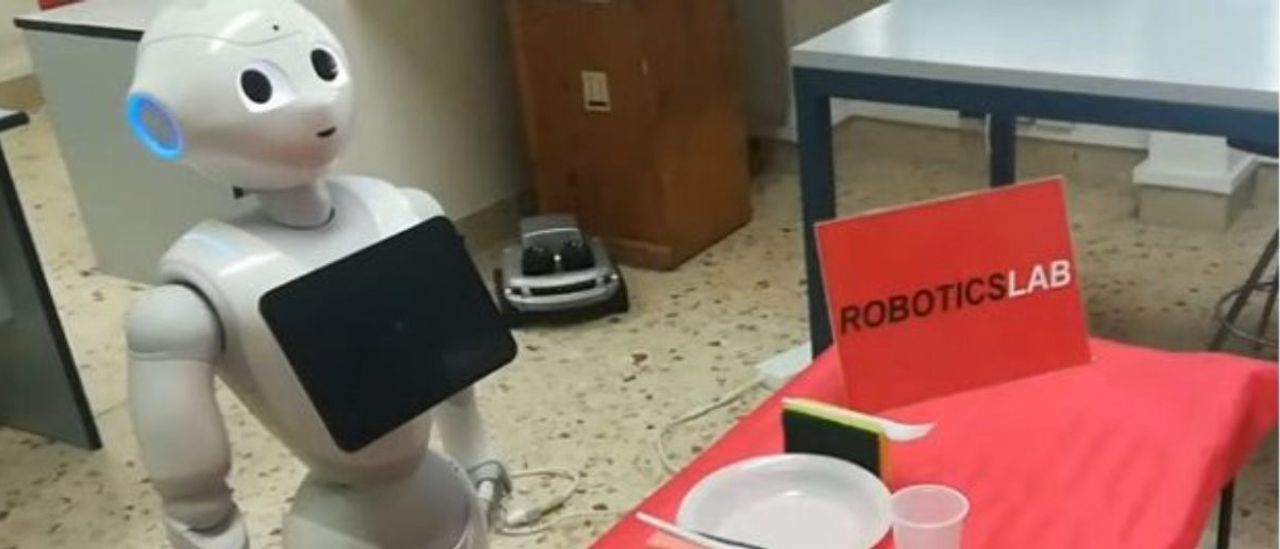 robot stands behind table with a Robotics Lab sign