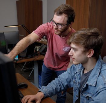 Two people in a room with a computer