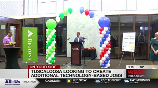 news screen capture of a man at a podium under a balloon arch