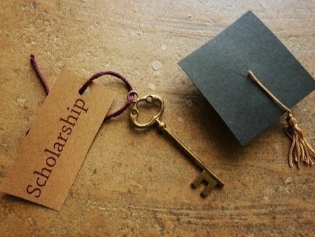 a key with the tag 'scholarship' tied to it and a paper graduation cap