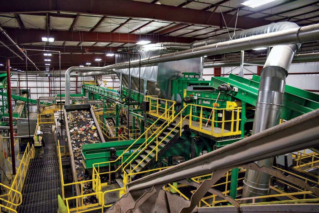 inside of a waste-to-fuels processing plant showing trash moving up a conveyor belt