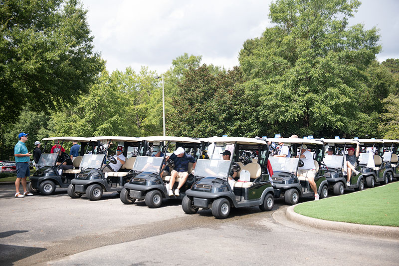 a ton of golf carts lined up with people in them
