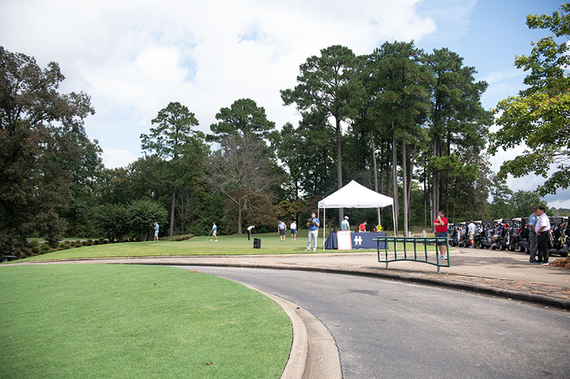 a small white tent on the right of a golf cart trail