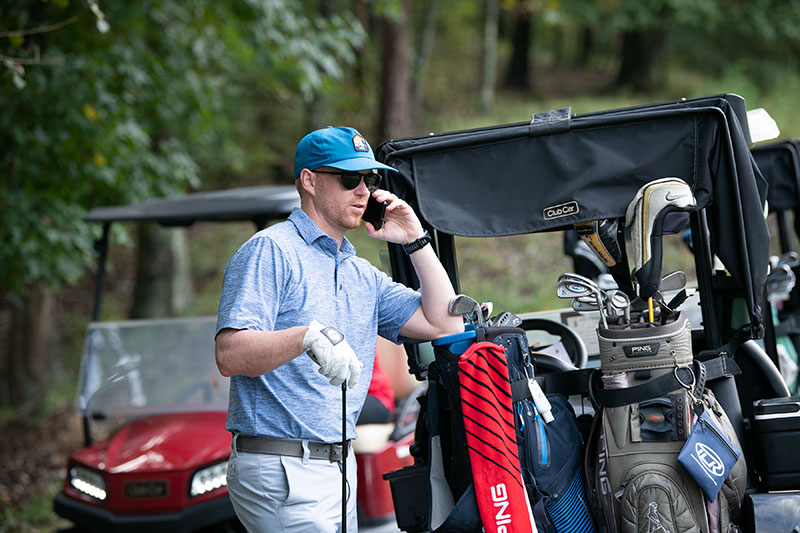 a man on his cellphone near a golf cart