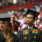 Students stand at a commencement ceremony