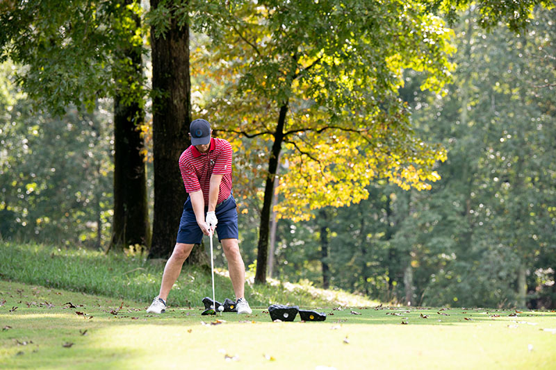 A golfer in red striped shirt lines up a shot