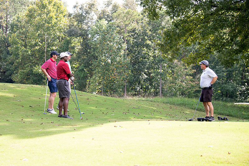 3 golfers on right side of picture chatting with another golfer in a white shirt on the right