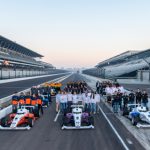 9 different teams stand behind their race cars on a race track