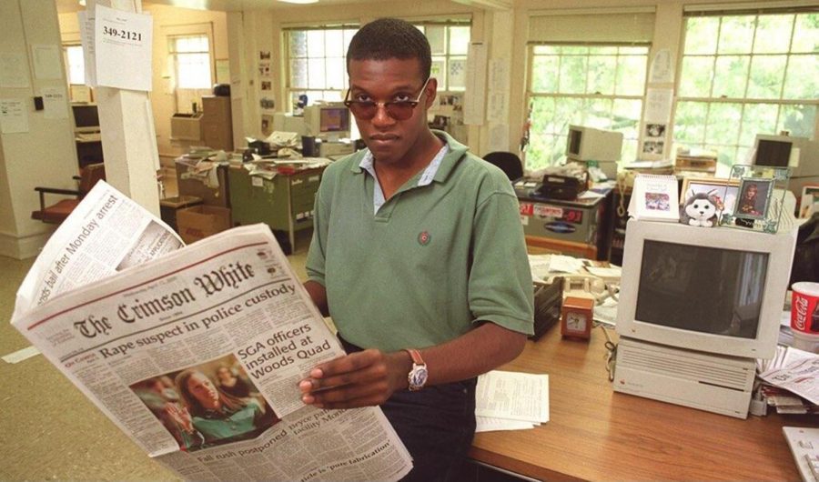 An older photo of a man in sunglasses holding a Crimson White newspaper