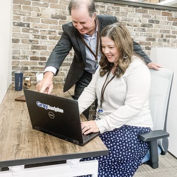 Dr. Gray points at a laptop screen while a student sits in front of it