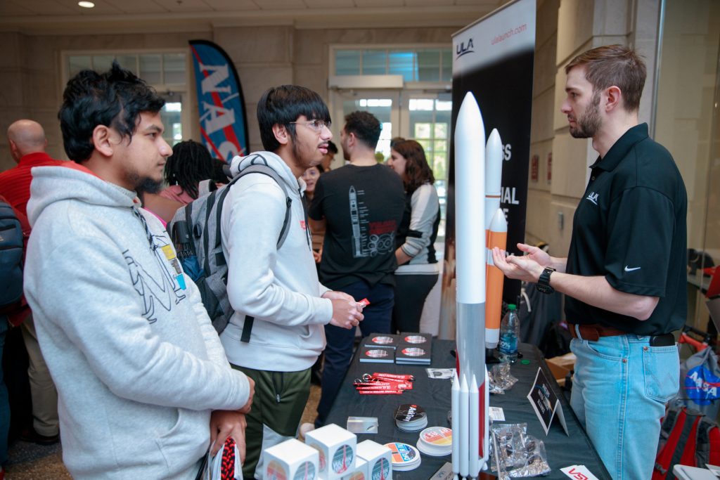 Students at a booth with a model rocket