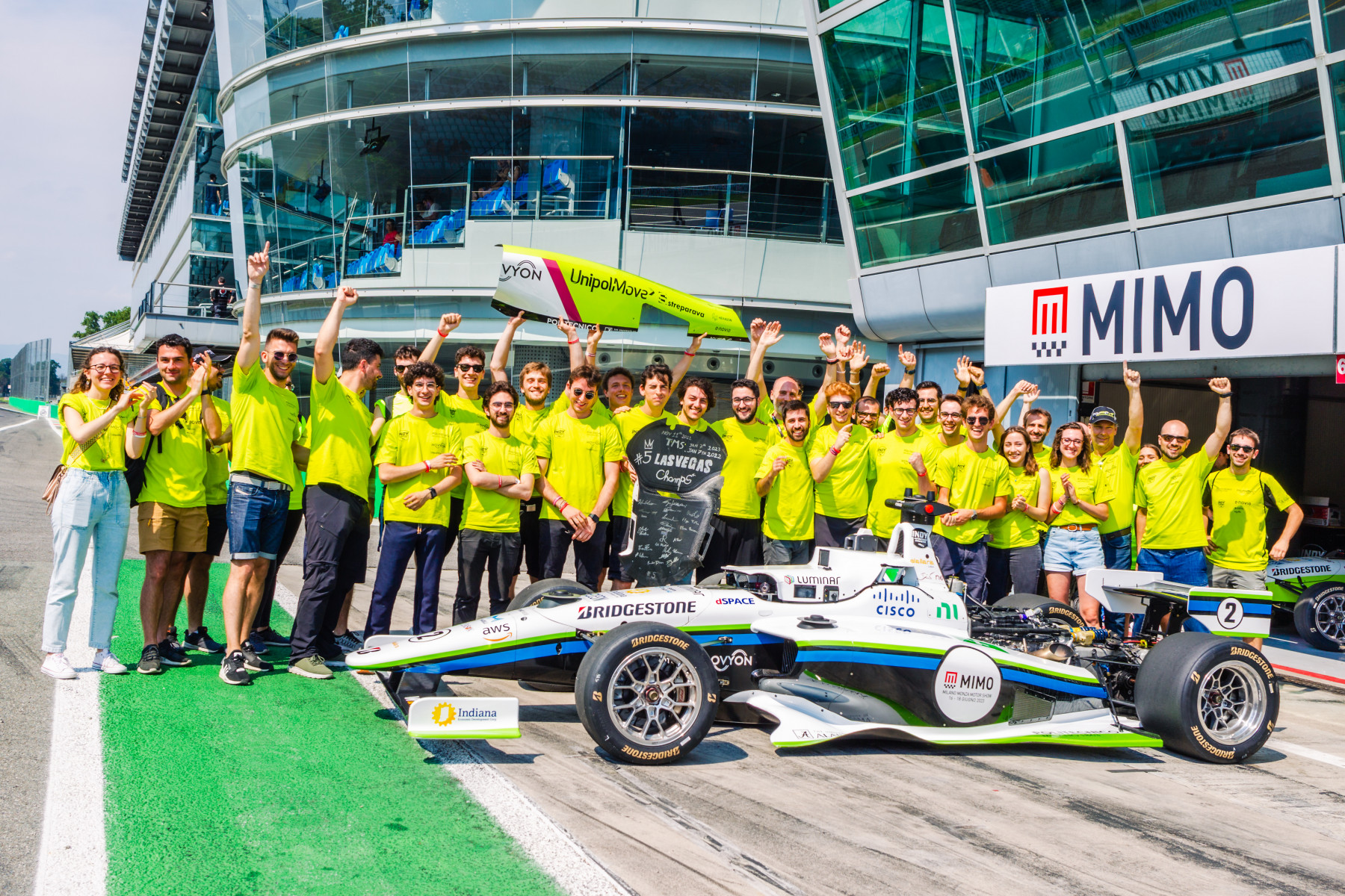 people outside lined up behind a race car