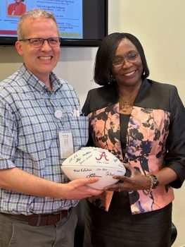 A man giving a woman a signed football