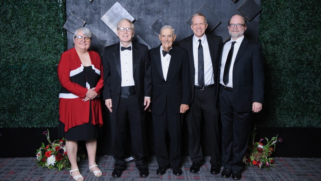 lady in a red dress and 4 men in suits