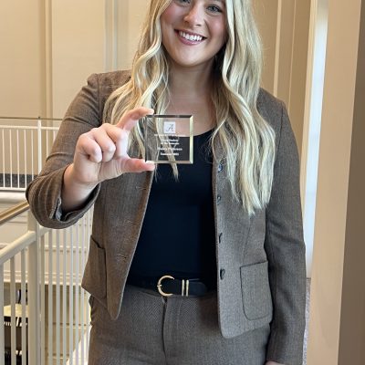 A student with blonde hair holds a glass award.
