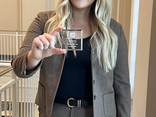 A student with blonde hair holds a glass award.