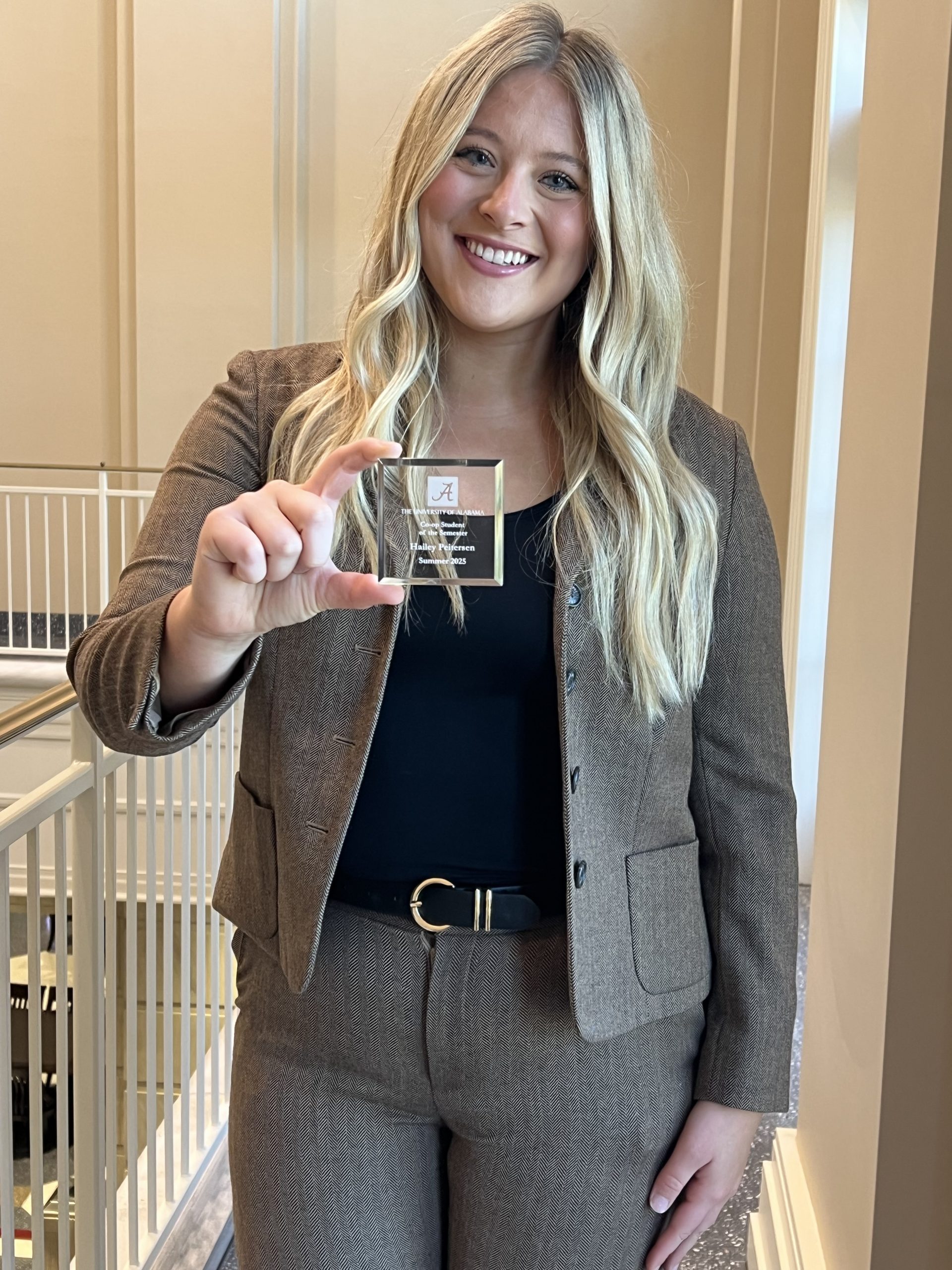 A student with blonde hair holds a glass award.