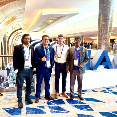 four men pose for a picture in a conference hall