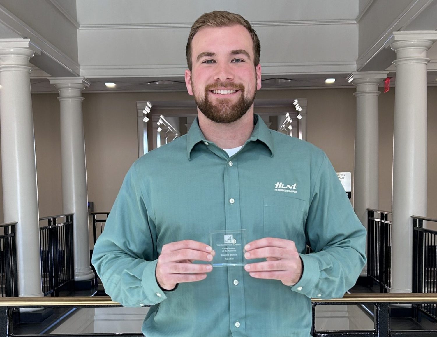 guy in a foyer holds an award