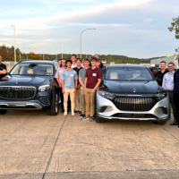 a group of students around 2 cars