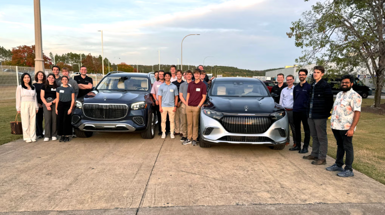 a group of students around 2 cars