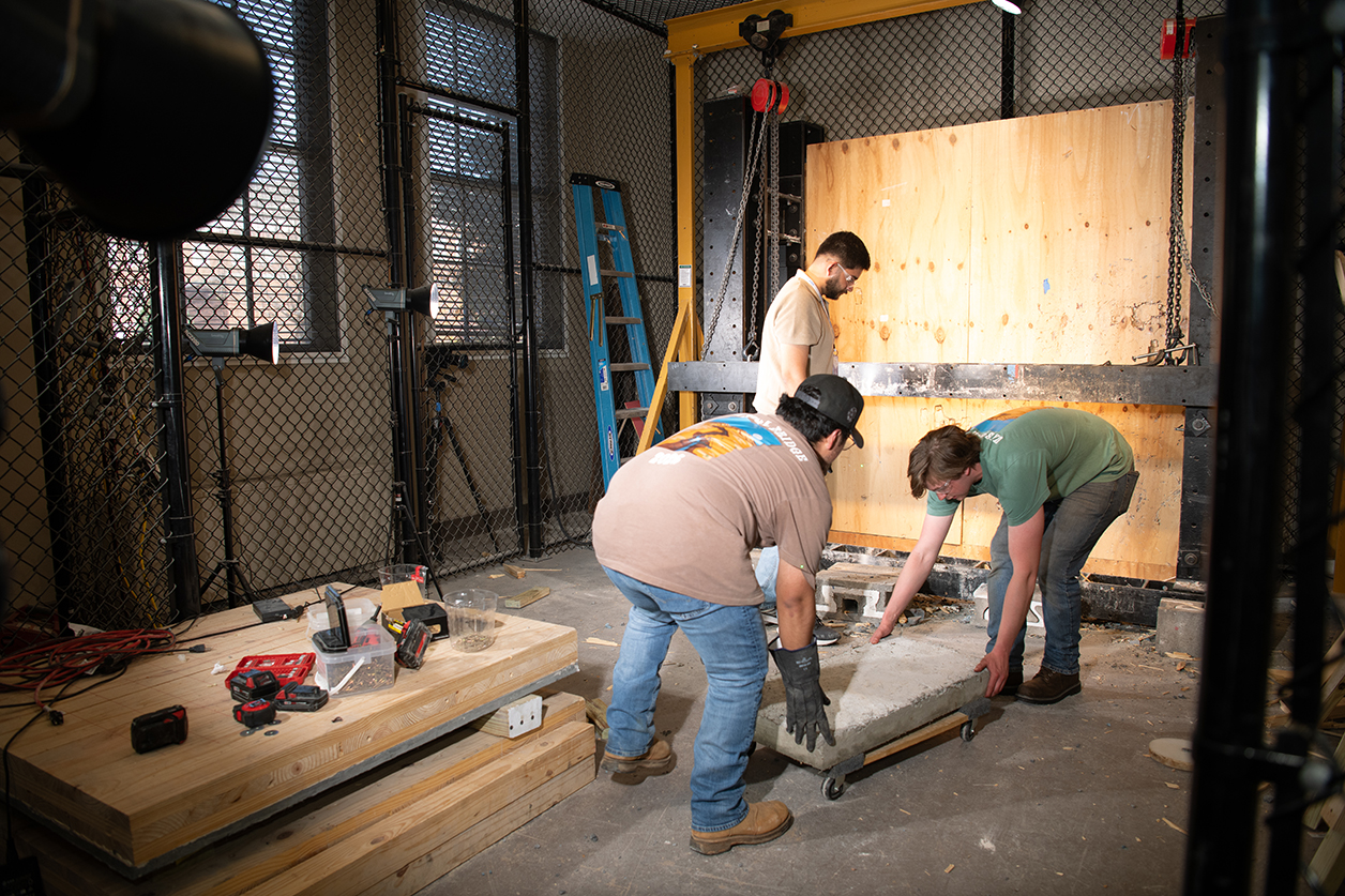 3 students working indoors with the debris cannon