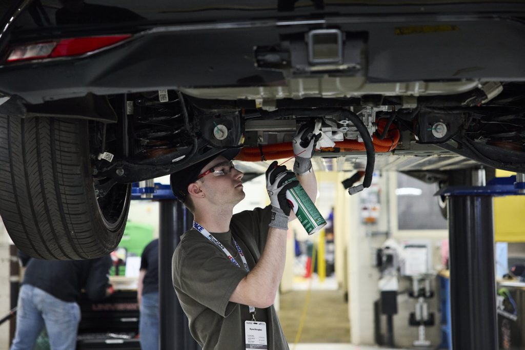 a student making modifications under the car